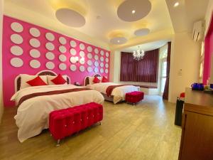 two beds in a bedroom with pink walls and red accents at Dream Ocean View B&B in Magong