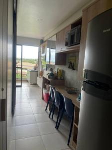 eine Küche mit einer Theke mit Stühlen und einem Kühlschrank in der Unterkunft Flat Eco Resort Carneiros in Rio Formoso
