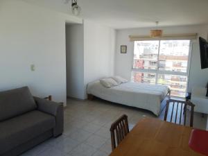 1 dormitorio con cama, sofá y mesa en Luminoso piso 10 con cochera en Mar del Plata