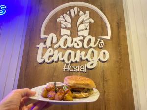 a person holding a plate with a sandwich and potatoes at Hotel Casa Tenango in Cobán