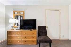 a bedroom with a dresser with a television and a chair at Cedarbrook Two Double bed Standard Hotel room 219 in Killington