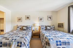 ein Schlafzimmer mit 2 Betten und einem Tisch mit einer Lampe in der Unterkunft Cedarbrook Deluxe one bedroom suite located on 2nd floor with outdoor heated pool 21921 in Killington