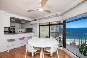 黄金海岸Beachfront & City View, Huge 2 Bedroom Apartment, Imperial Surf Resort的一间带白色桌椅的用餐室和一个阳台