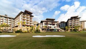 a large building with a grass field in front of it at Arcadia Resort Hainan in Lingshui