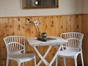 uma mesa branca com duas cadeiras e uma flor sobre ela em Harbour View Cottage Bay of Islands em Opua