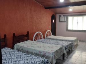 three beds in a room with red walls and a window at Recanto dos Loureiros in Saquarema