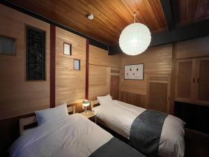 a bedroom with two beds and a light fixture at 高松市一軒家貸切プライベートハウスotonarisan-駐車場無料 in Takamatsu