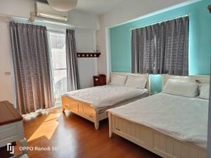 two beds in a room with blue walls and windows at 茶樂二重奏 in Taitung City
