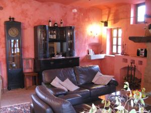 a living room with a leather couch and a clock at Apartment with large covered terrace in small residence with swimming pool in Bastia Mondovì