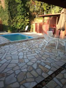 a patio with a table and chairs next to a pool at Casa com Piscina a 100 m. de Camburizinho in Camburi
