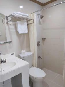 y baño blanco con aseo y ducha. en PHELA GRANDE HOTEL en General Santos