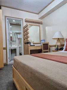 a bedroom with a bed and a desk and a mirror at PHELA GRANDE HOTEL in General Santos