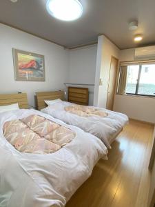 Duas camas brancas num quarto com uma janela em 君の家 東寺 em Quioto