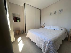 1 dormitorio con cama blanca y espejo en Depto acogedor, moderno y espacioso en Rosario