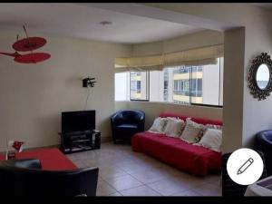 a living room with a red bed and a tv at Espacioso departamento in Lima