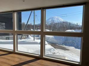 a view of a snow covered mountain through a window at Soga House in Kabayama