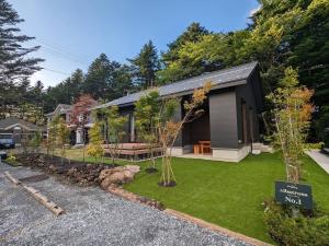 una pequeña casa negra con un patio de césped en Albatross Karuizawa en Karuizawa