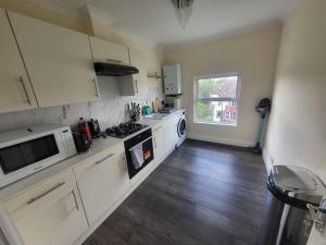 a kitchen with white appliances and a wooden floor at Entire South London Apartment hosted by Pius in Croydon
