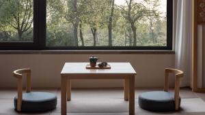 a table and two chairs with a table and a window at Hyakumangoku Onsen Hotel in Shanghai