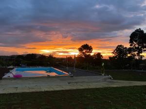 a person standing next to a swimming pool at sunset at Concetta Tourist Inn Apartelle with Pool in Manolo Fortich