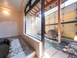 a room with a shower with a large window at Tabist Fuji Sakura Onsen Ryokan in Fuefuki