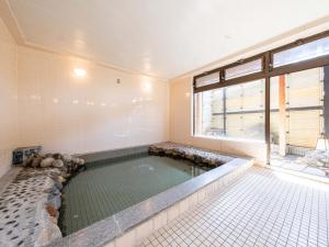 a swimming pool in a room with a large window at Tabist Fuji Sakura Onsen Ryokan in Fuefuki