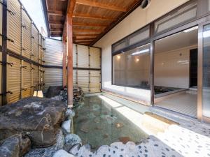 a japanese house with a pond in the floor at Tabist Fuji Sakura Onsen Ryokan in Fuefuki