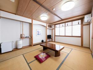 ein Wohnzimmer mit einem Tisch und einem Fenster in der Unterkunft Tabist Fuji Sakura Onsen Ryokan in Fuefuki