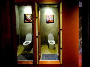 two toilets in a bathroom with two urinals at Rinvada House in Bangkok