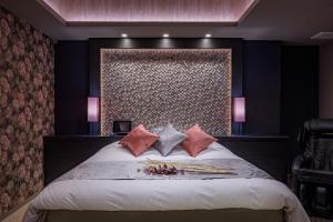 ein Schlafzimmer mit einem großen Bett mit rosa Kissen in der Unterkunft ホテル シードット 横浜 トレ in Yokohama