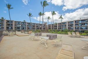 a large courtyard with chairs and tables and palm trees at Hale Ono Loa 114- Ground floor partial ocean view gem in Kahana