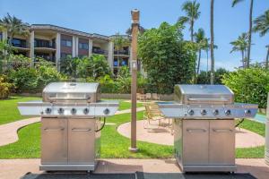 two bbqurgers on a patio in front of a building at Hale Ono Loa 114- Ground floor partial ocean view gem in Kahana