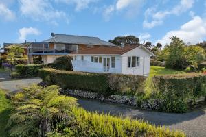 une maison blanche avec des buissons devant une maison dans l'établissement Okiato Views - Russell Holiday Home, à Russell