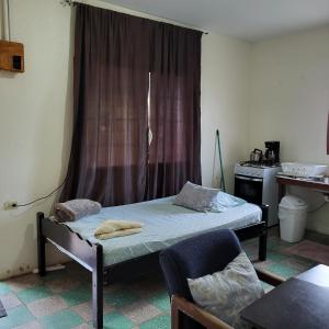 um pequeno quarto com uma cama e uma janela em Hacienda Tropical Guest House em Belmopan