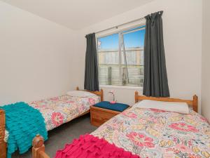 a bedroom with two beds and a window at A Sunshine Retreat - Pauanui Holiday Home in Pauanui