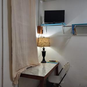 a table with a lamp and a laptop on a wall at Hacienda Tropical Guest House in Belmopan