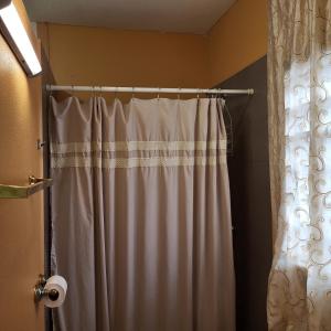 a white shower curtain in a bathroom with a shower curtain at Hacienda Tropical Guest House in Belmopan