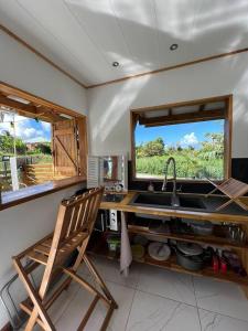 eine Küche mit einer Spüle und einem Holzstuhl in der Unterkunft TINY HOUSE avec vues in Capesterre-Belle-Eau