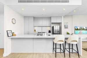 a kitchen with white cabinets and bar stools at Amazing city view high level Apt in Sydney