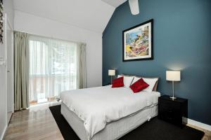 een slaapkamer met blauwe muren en een bed met rode kussens bij Fantastic Beachside Townhouse in Victor Harbor