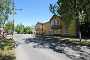 an empty street in front of a yellow house at Karusselli 1 Apartments in Pärnu