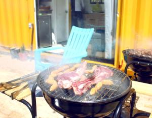 a grill with meat and cookies on it with a blue chair at Libre Camp Amarillo in Nemocón
