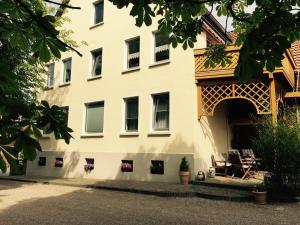 ein großes weißes Gebäude mit einer Terrasse davor in der Unterkunft Ferienwohnung Landhaus Hohenstein, Schwimmteich, ruhige Lage in Hessisch Oldendorf