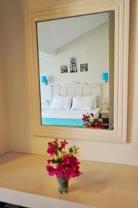 a mirror in a bedroom with a vase of flowers on a table at Bora Hotel in Datca