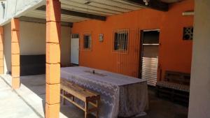 una habitación con una pared de color naranja con una mesa y un banco en Casa de temporada em Cabuçu, en Saubara