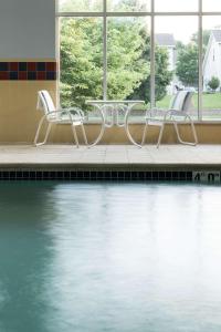 three chairs and a table next to a swimming pool at Hampton Inn Kansas City Liberty in Liberty