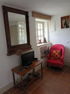 a living room with a television and a red chair at Annexe indépendante in Bourron-Marlotte