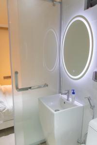 a white bathroom with a sink and a mirror at Fanfini Residence Male’ in Male City