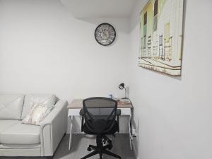 ein Büro mit einem Schreibtisch, einem Stuhl und einer Uhr in der Unterkunft New built house, Stay in Style Guest Suite, 2bedroom, 2bed, 2bath in Edmonton
