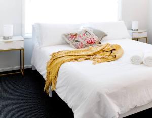 Una cama blanca con una manta amarilla. en Spacious Two-Bedroom Retreat, en Ipswich